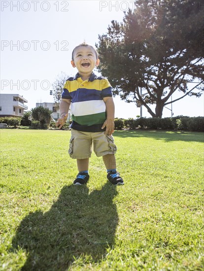 Hispanic boy standing on grass in park