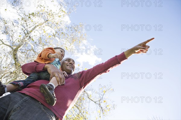 Low angle view of Hispanic father and son pointing outdoors