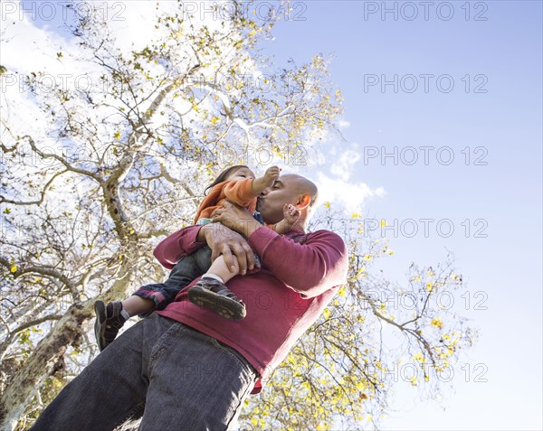 Low angle view of Hispanic father kissing son outdoors