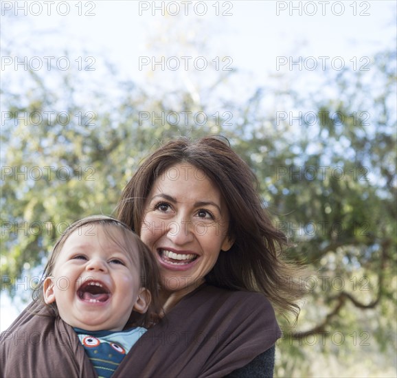 Hispanic mother wearing son in carrier outdoors