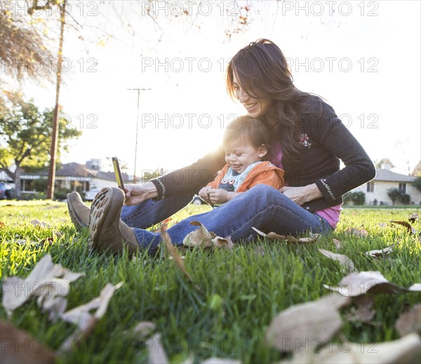 Hispanic mother taking selfie with son in park