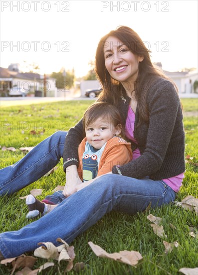 Hispanic mother sitting with son in park