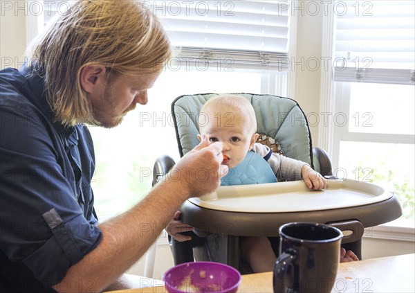 Caucasian father feeding son in high chair