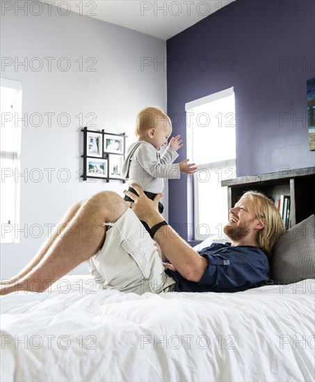 Caucasian father and son playing on bed