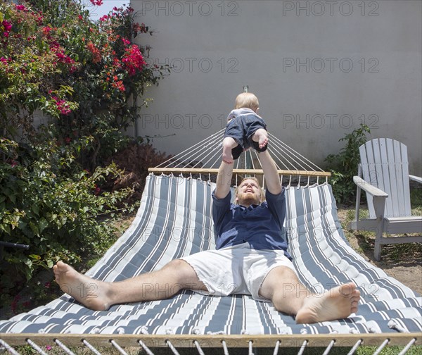 Caucasian father and son playing on hammock