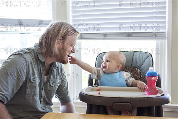 Caucasian father feeding son in high chair