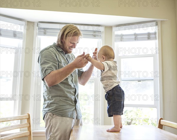 Caucasian father teaching son to stand on table