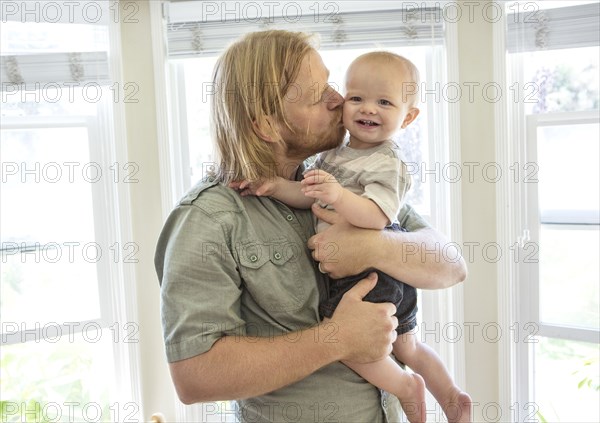 Caucasian father kissing son indoors
