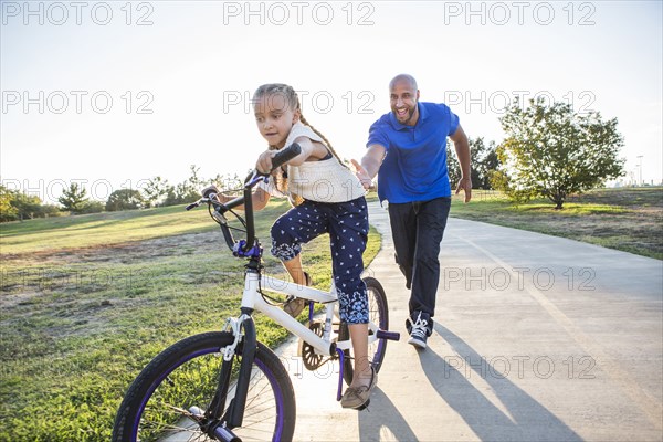 Father teaching daughter to ride bicycle in park