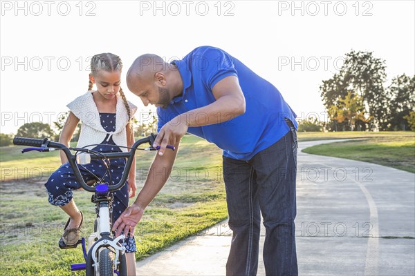 Father teaching daughter to ride bicycle in park