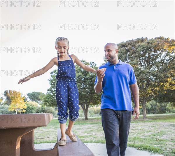 Father and daughter playing on picnic table in park