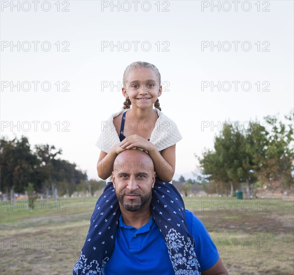 Father carrying daughter on shoulders in park