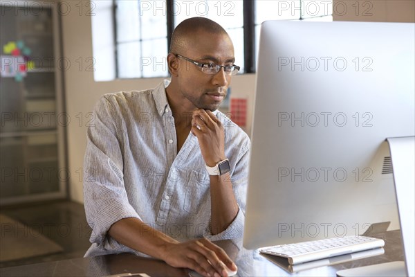 Mixed race businessman using computer in office