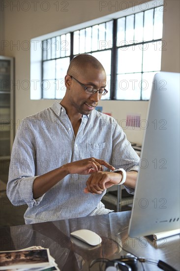 Mixed race businessman checking his watch in office