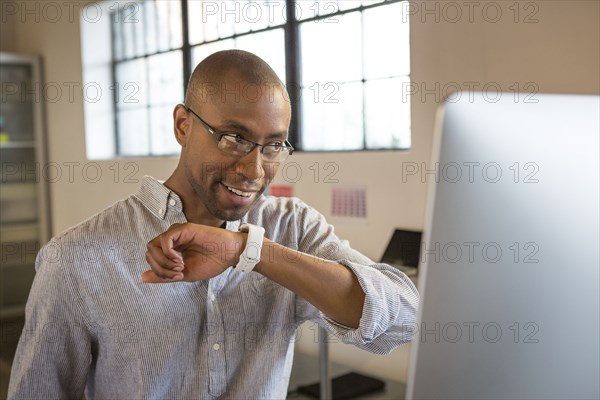 Mixed race businessman talking into smart watch in office