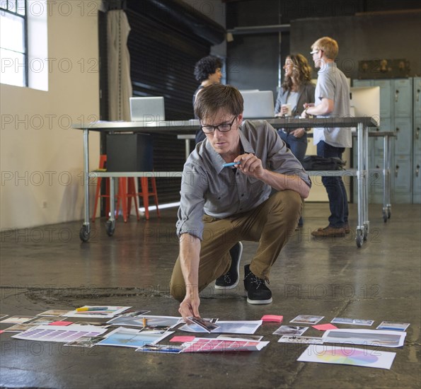 Caucasian businessman examining paperwork on office floor