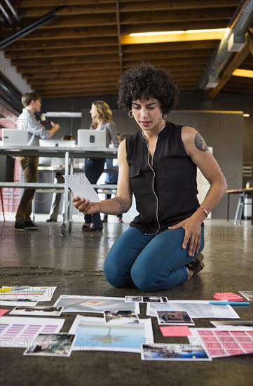 Businesswoman examining paperwork on office floor