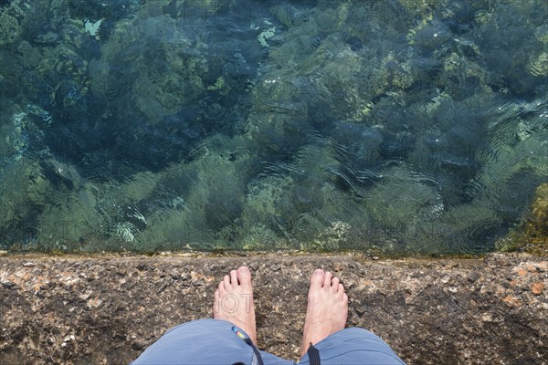 Caucasian man standing on rock wall over water