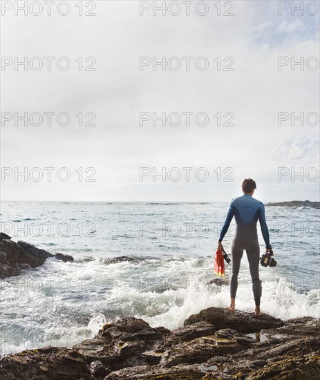 Hispanic diver wearing wetsuit on beach