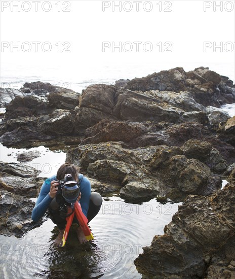 Hispanic diver photographing on beach