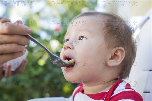 Mixed race mother feeding baby outdoors