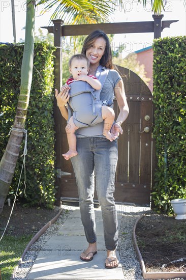 Mixed race mother carrying baby in sling