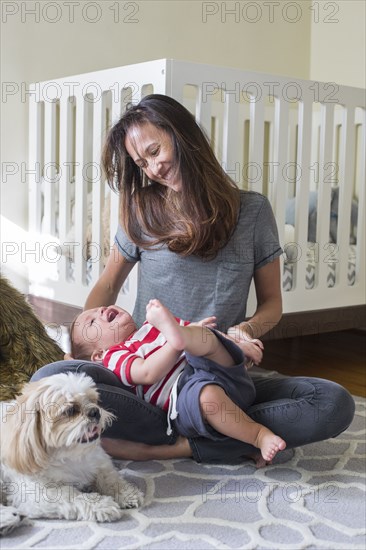 Mixed race mother playing with baby in nursery