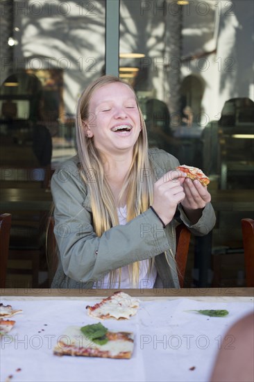 Caucasian girl eating pizza in cafe