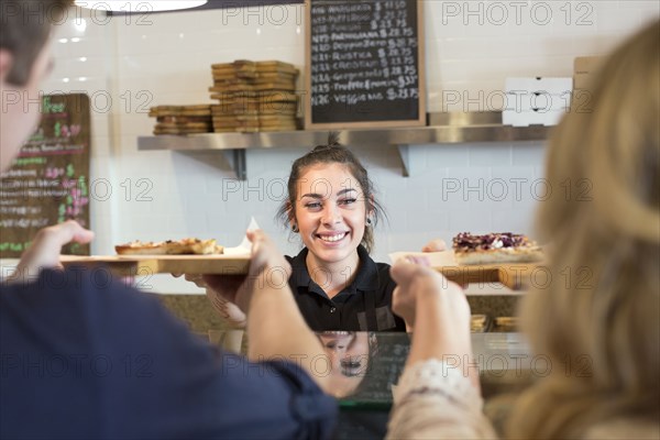 Server handing pizza to customers in cafe