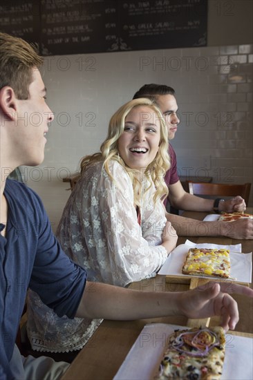 Caucasian friends eating pizza in cafe