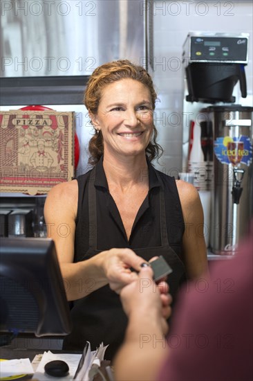 Server helping customer purchase pizza in cafe