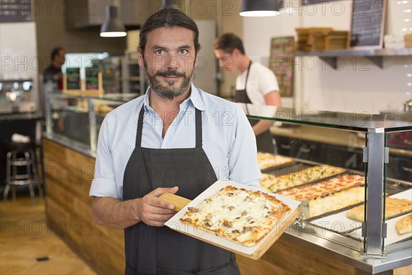 Server holding pizza in cafe