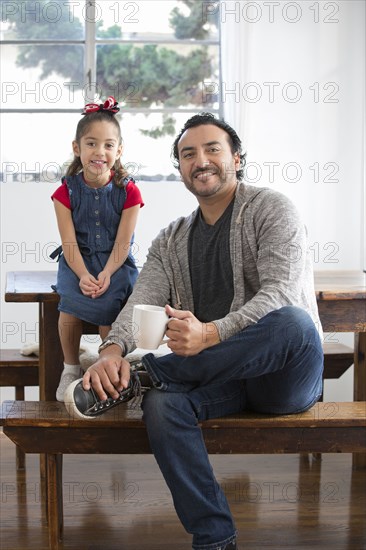 Hispanic father and daughter smiling at table