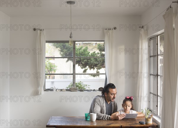 Hispanic father and daughter using digital tablet