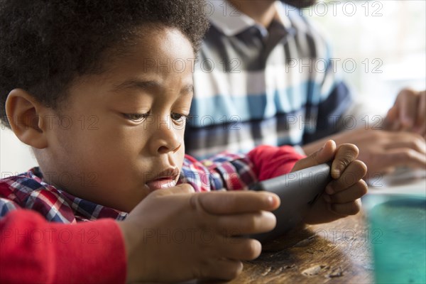 Mixed race boy using cell phone at table