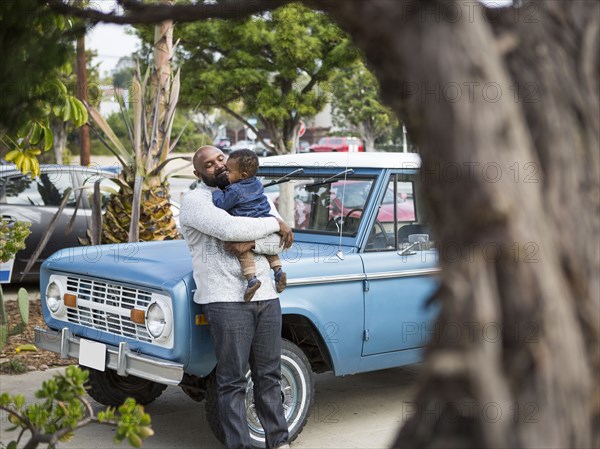 African American father holding son at truck