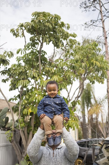 African American father carrying son outdoors