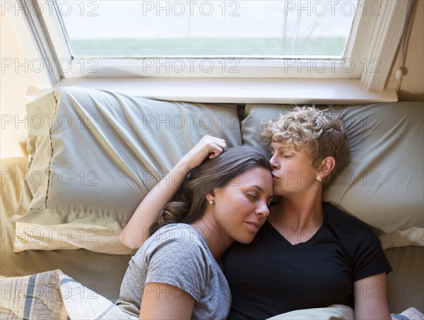 Caucasian lesbian couple kissing in bed