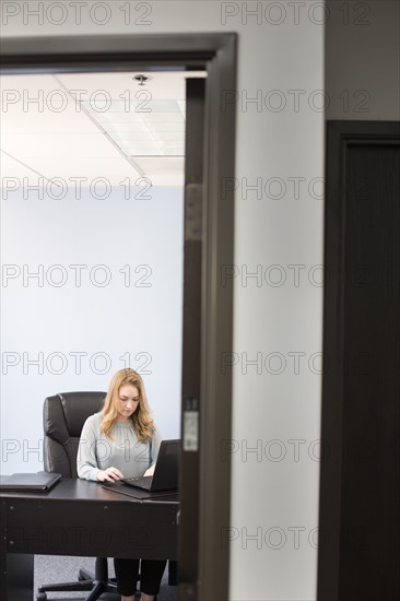 Caucasian businesswoman using laptop in office