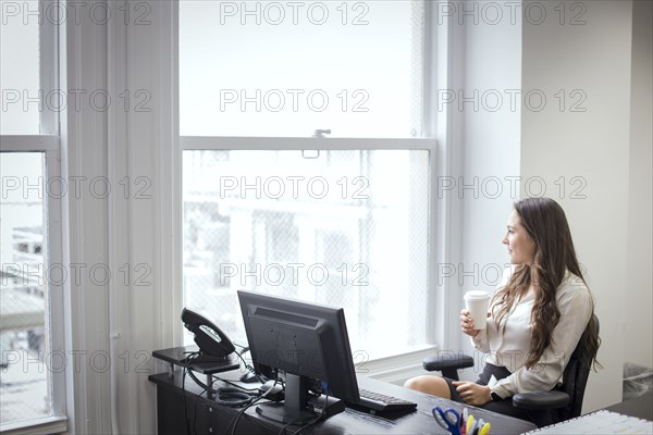 Caucasian businesswoman looking out office window