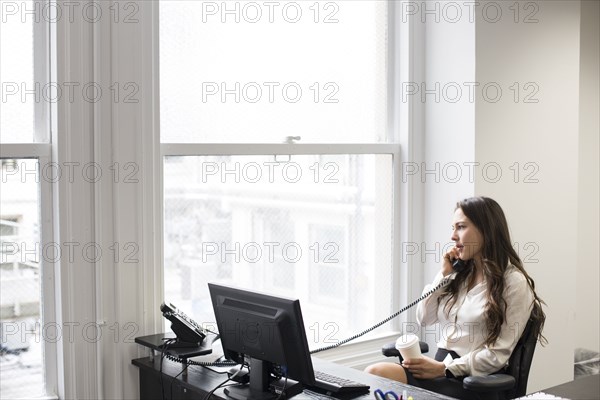 Caucasian businesswoman talking on telephone in office