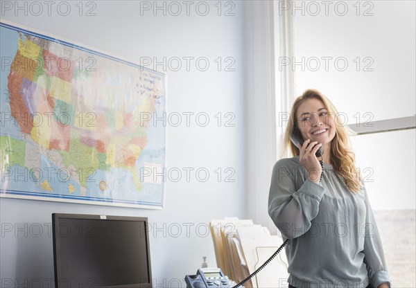 Caucasian businesswoman talking on telephone in office