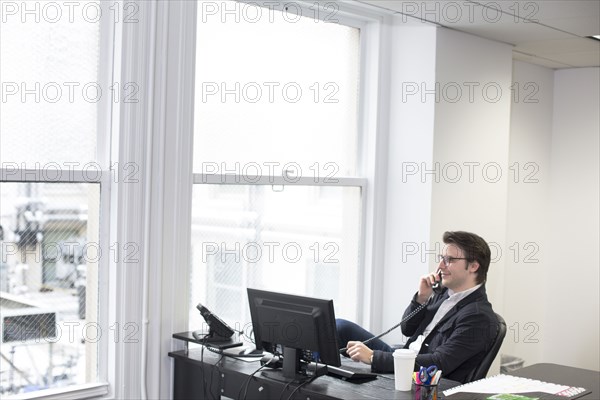 Caucasian businessman talking on telephone in office