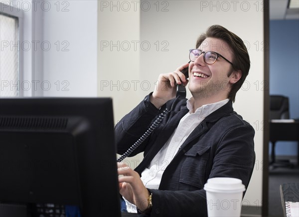 Caucasian businessman talking on telephone in office