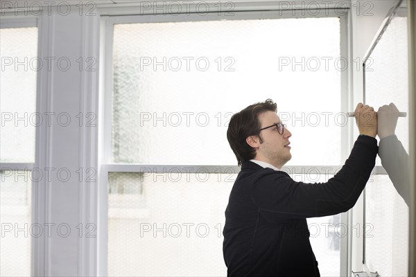 Caucasian businessman writing on whiteboard in office