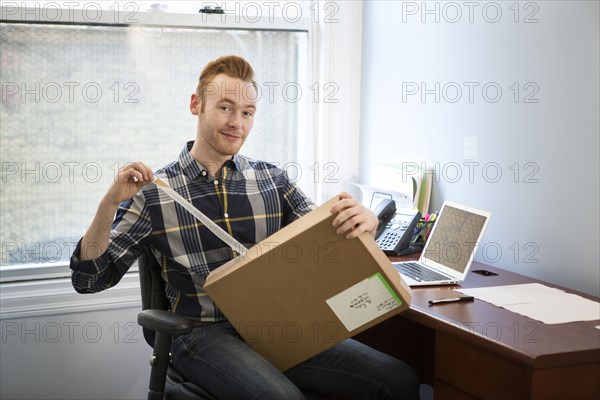 Caucasian businessman opening package in office