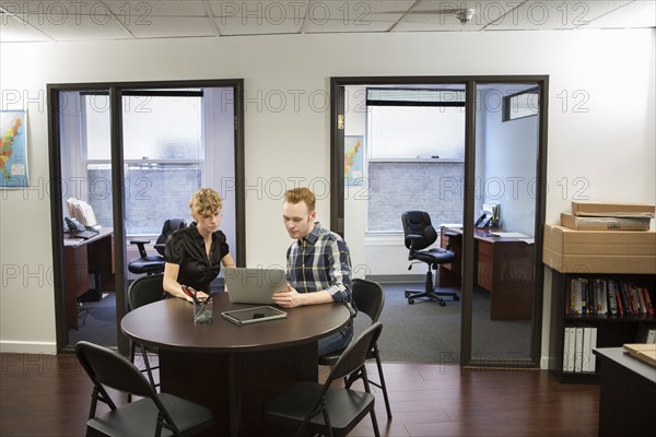 Caucasian business people using laptop in office