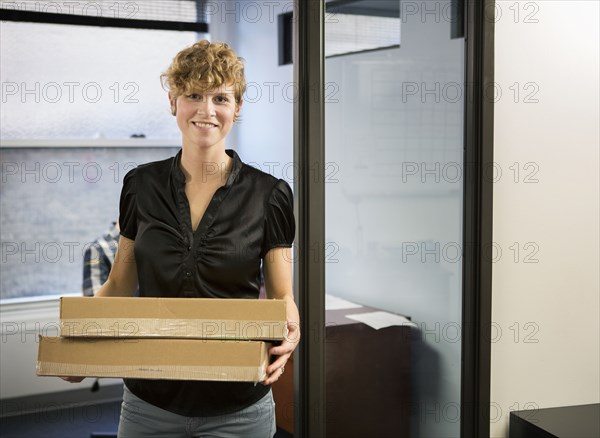 Caucasian businesswoman holding packages in office