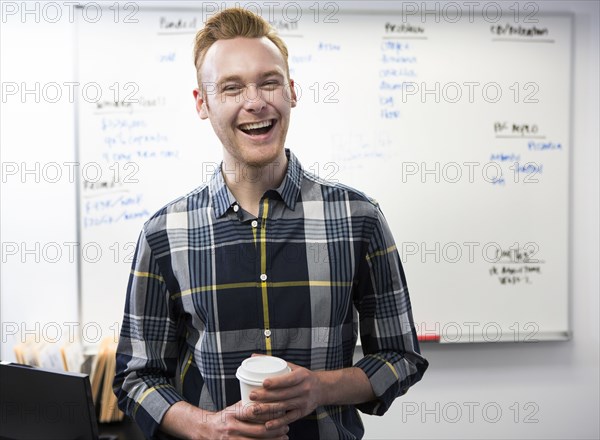 Caucasian businessman drinking coffee in office