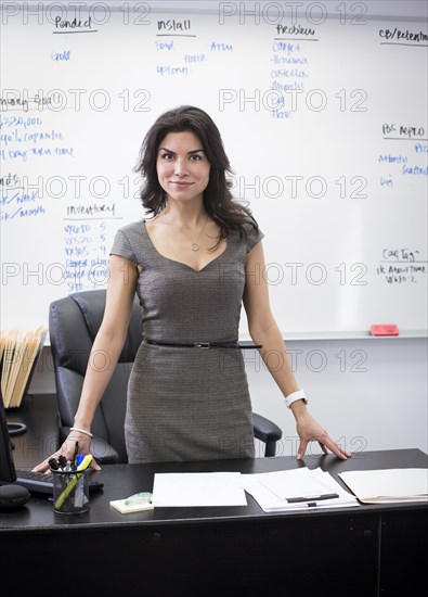 Mixed race businesswoman standing at desk in office